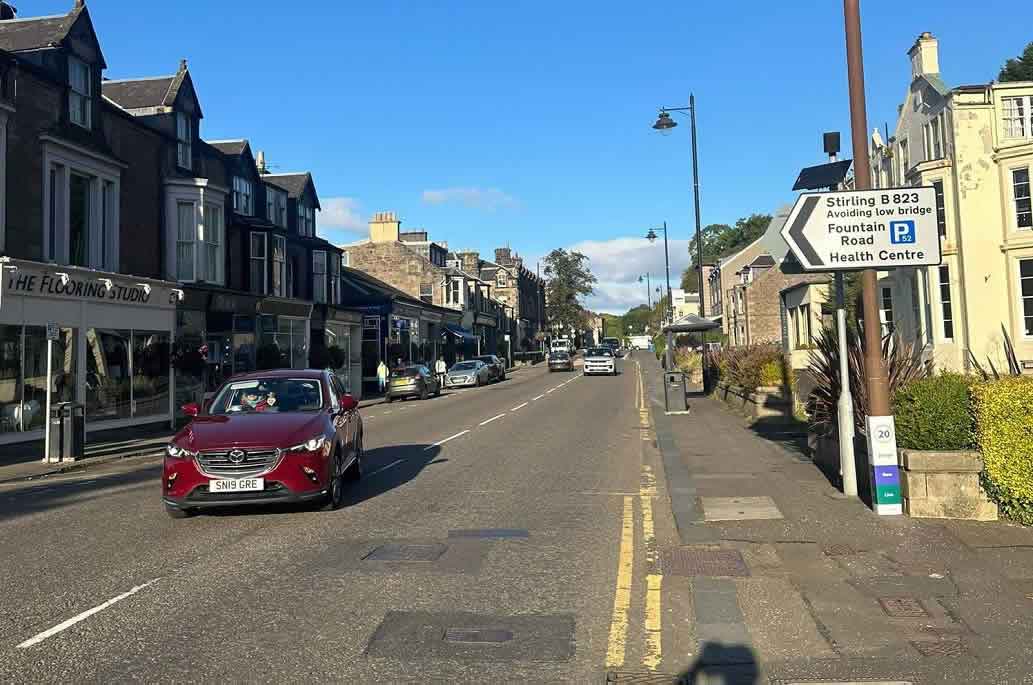 Traditional stone buildings and shops along a street in Bridge of Allan